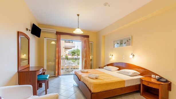 Une chambre d’hôtel comprenant un lit, une table de chevet, une chaise, un bureau et donnant sur l’extérieur.