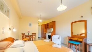 Una camera d'albergo con un letto, una scrivania, una sedia, uno specchio e angolo cottura.