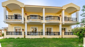 Un edificio a più piani con balconi, un tetto piatto e un prato curato.