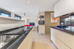 A modern kitchen with a black countertop, stainless steel sink, and a built-in oven.