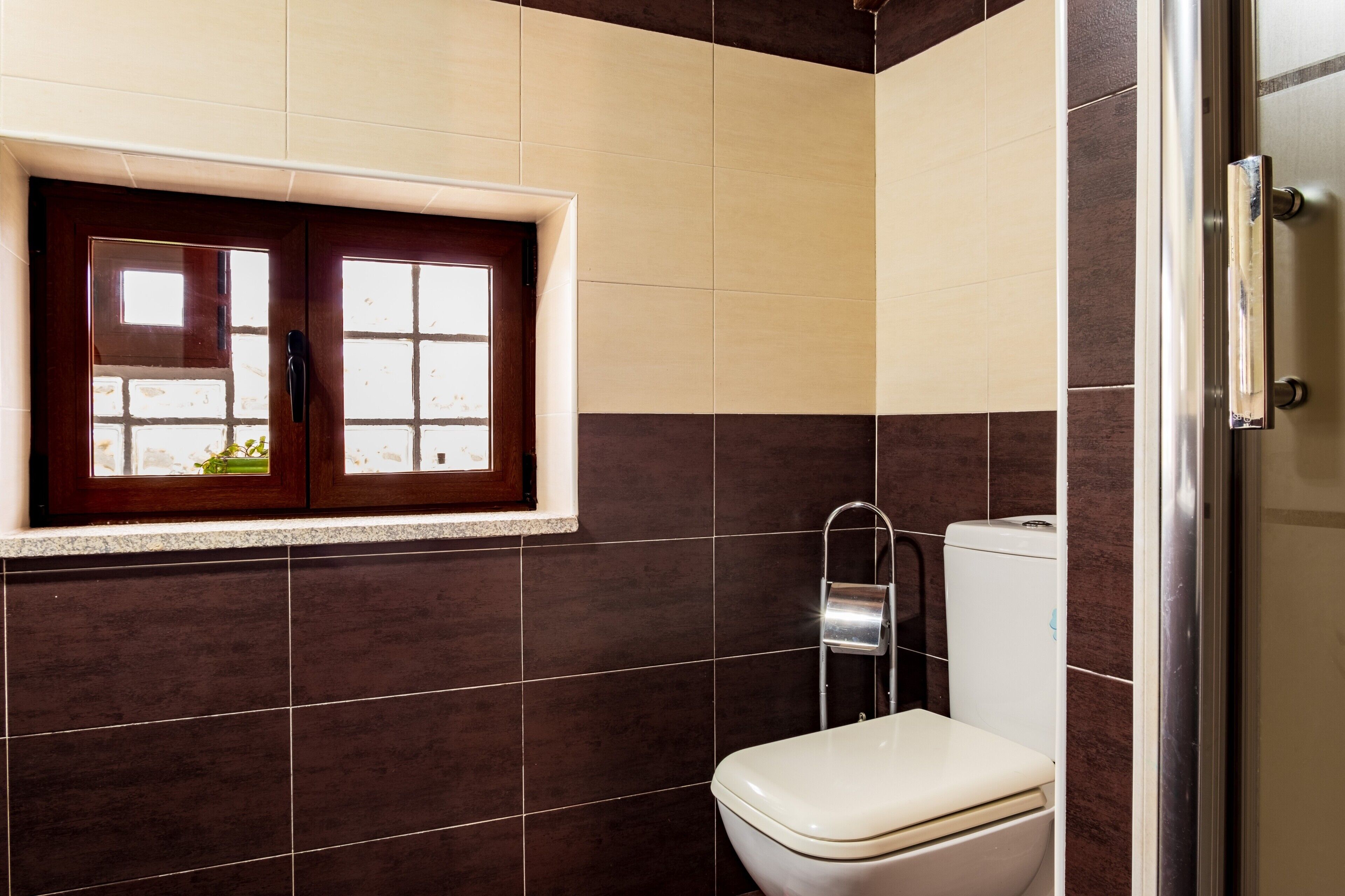 A bathroom with a toilet, a window, and a shower area.