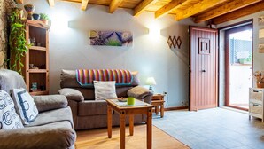 A cozy living room with a sofa, a wooden coffee table, a lamp, and a door leading outside.