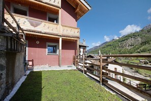 A two-story building with a balcony, a wooden fence, and a view of a mountainous landscape.