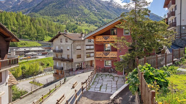 A mountain village with traditional buildings, a paved street, and a view of snow-capped mountains. - Apartment 'Maison De La Musique' with Mountain View, Shared Terrace and Wi-Fi (Cogne)