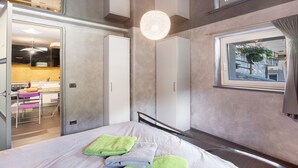 A bedroom with a bed, a window with a view, a hanging light fixture, and a door leading to a bathroom. - Apartment 'Maison De La Musique' with Mountain View, Shared Terrace and Wi-Fi (Cogne)