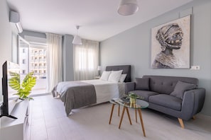 Ein modernes Schlafzimmer mit einem Bett, einem grauen Sofa und einem Bild an der Wand.