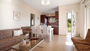 Una sala de estar moderna con un sofá, una mesa de comedor, sillas y una cocina al fondo.