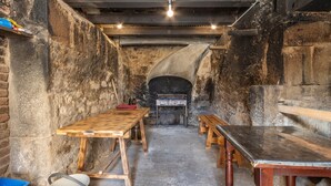 Una habitación rústica con una mesa de madera, un banco y una chimenea.