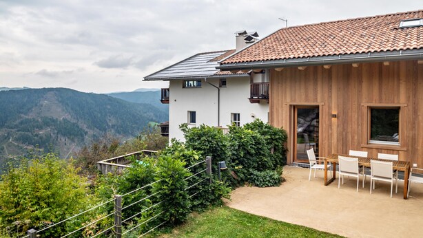 A modern house with a white exterior, wooden paneling, and a tiled roof. - Apartment 'Latemar' with Mountain View, Shared Garden and Wi-Fi (Nova Ponente)