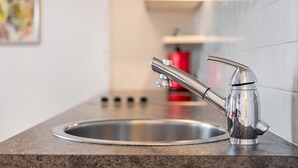 A kitchen with a stainless steel sink, a modern faucet, and a red fire extinguisher on the wall. - Apartment 'Latemar' with Mountain View, Shared Garden and Wi-Fi (Nova Ponente)