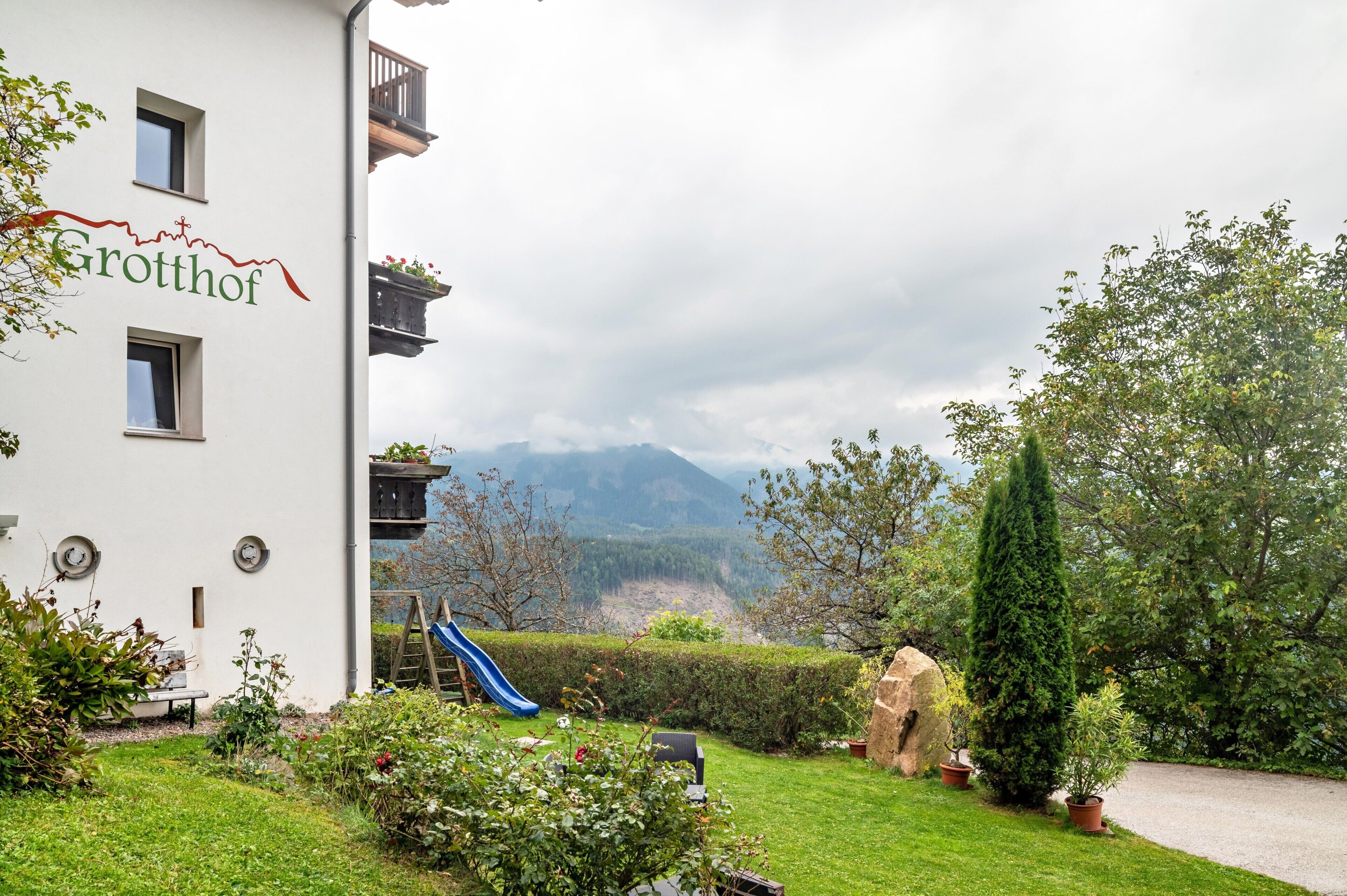 Un edificio con un letrero que dice 'Grotthof', un tobogán azul y vistas de montañas.