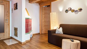 Techo de madera, un sofá marrón, un taburete de madera y una pared con decoraciones hexagonales.