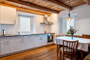 Une cuisine moderne avec des armoires blanches, une hotte de cuisinière en acier inoxydable et un plafond en bois.