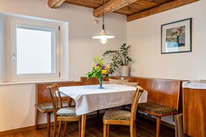 Un coin repas comprenant une table, des chaises, un vase de fleurs, un banc et un tableau accroché au mur.