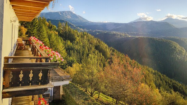 Un balcón de madera con vista a un paisaje montañoso.