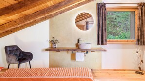 A bedroom with a wooden ceiling, a round mirror, a window with curtains, a bed with an orange checkered bedspread, and a chair. - Chalet 'Himmel' with Mountain View, Private Garden and Wi-Fi (Nova Ponente)