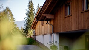 A wooden house with a garage, a driveway, and a small garden area. - Chalet 'Himmel' with Mountain View, Private Garden and Wi-Fi (Nova Ponente)