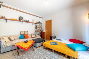 Une pièce comprenant un canapé, un lit, une petite table et une étagère sur laquelle sont disposés divers objets.