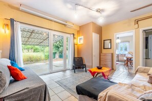 Une pièce comprenant un lit, une chaise, une table et une porte-fenêtre coulissante donnant sur un espace extérieur.