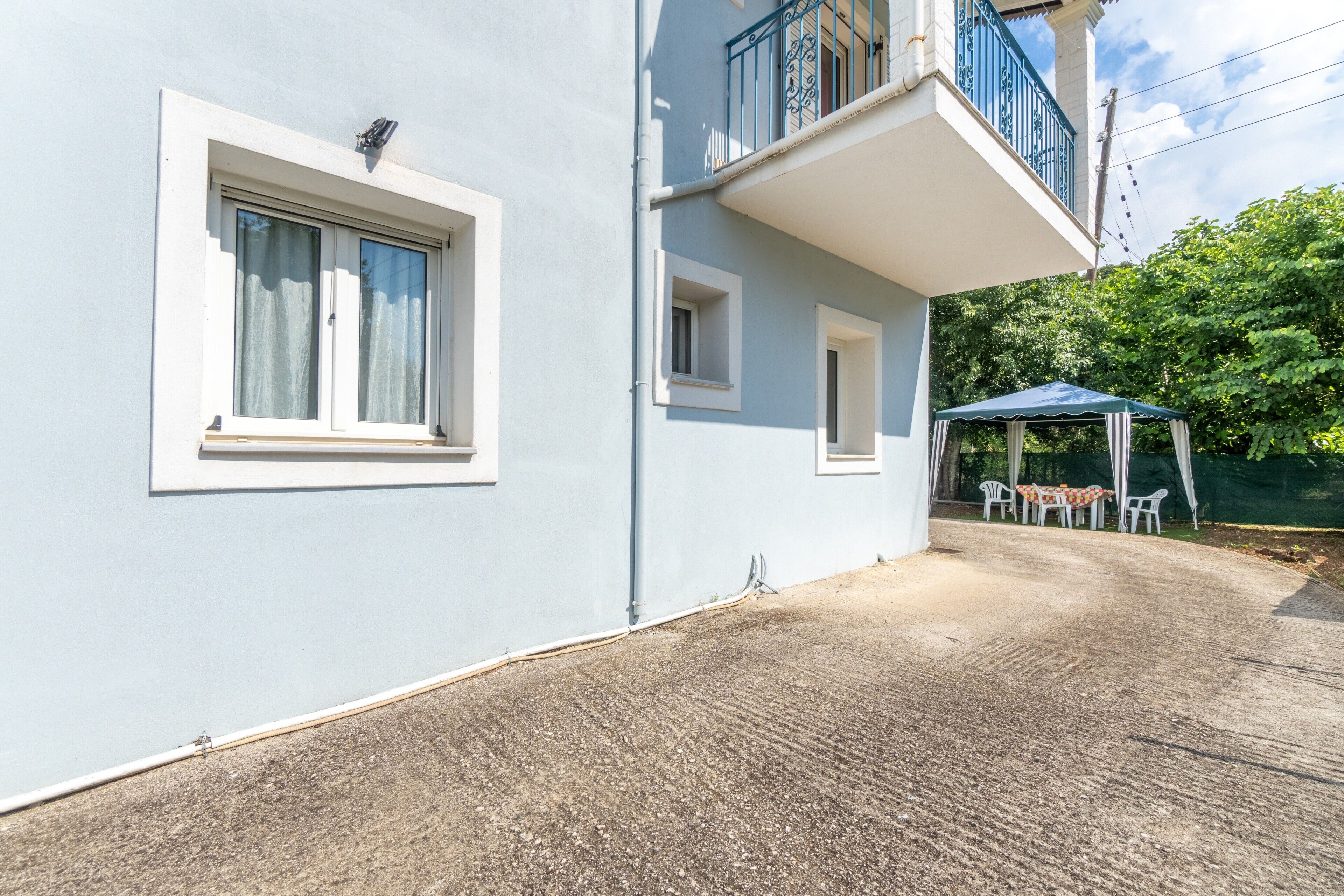 Un bâtiment doté d’un balcon, d’un espace extérieur couvert aménagé en coin salon et d’une fenêtre avec des rideaux.