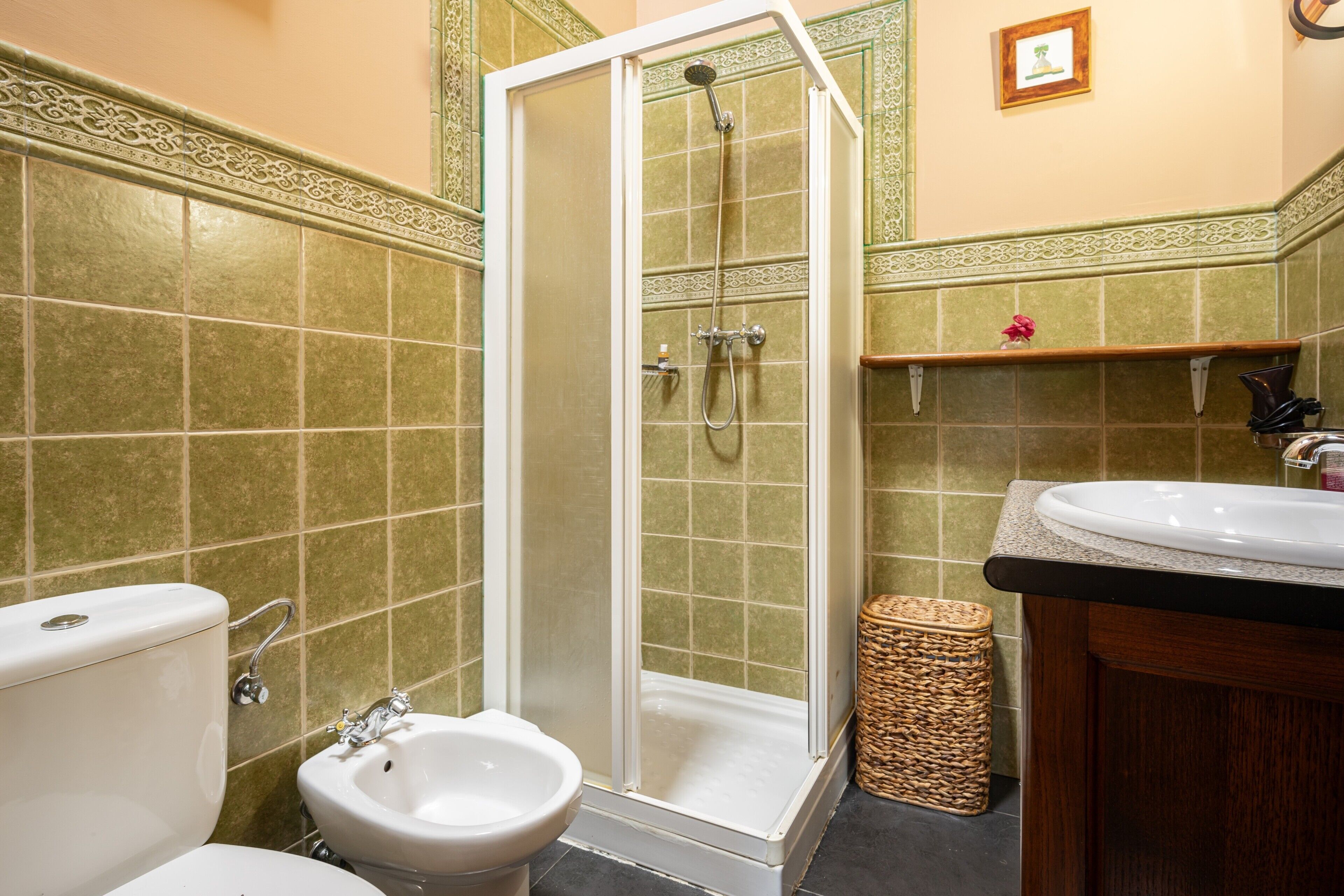 A bathroom with a shower, toilet, bidet, and sink.