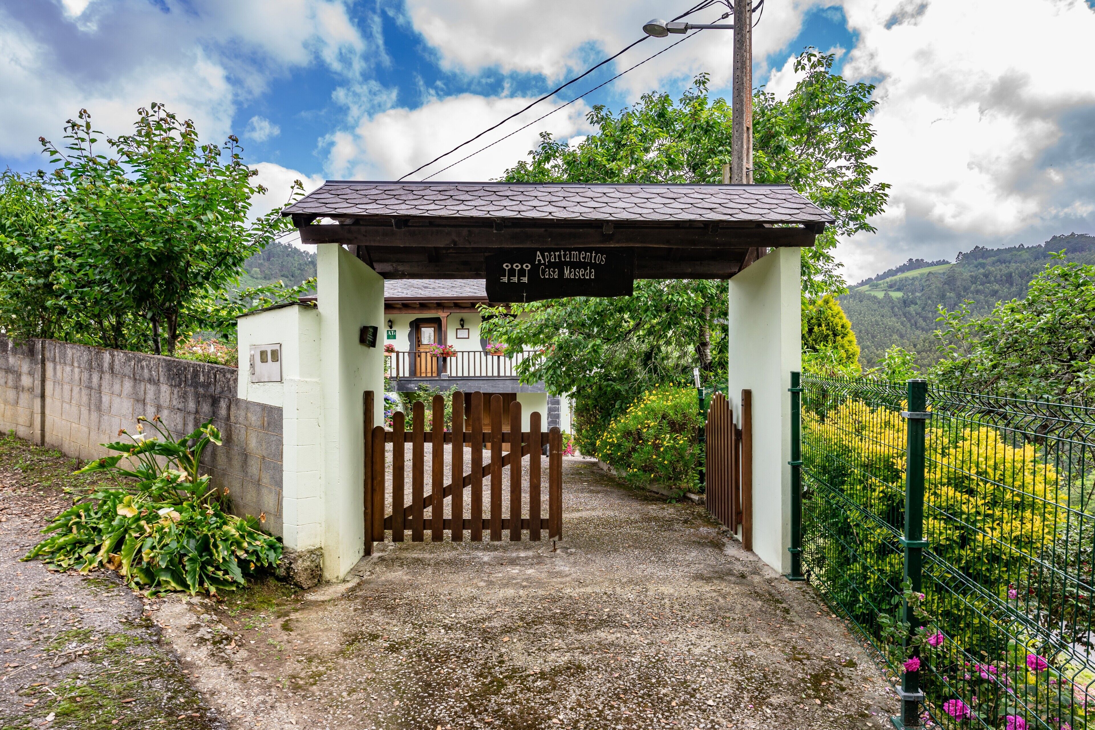 Une entrée fermée par un portail mène à un immeuble sur lequel est apposée une enseigne indiquant « Apartamentos Casa Maseda ».
