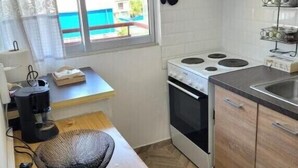 Une cuisine de taille réduite, équipée d’une cuisinière, d’un four et d’une petite fenêtre avec des rideaux.