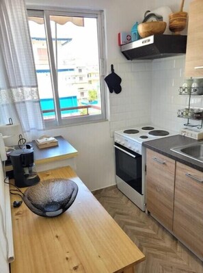 A compact kitchen with a stove, oven, and a small window with curtains.