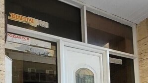 Une porte blanche avec un panneau de verre, une fenêtre au-dessus et une enseigne avec du texte en caractères cyrilliques.