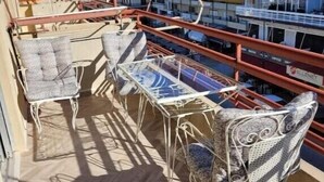 Un balcon avec deux chaises et une table, donnant sur une région montagneuse parsemée de bâtiments.