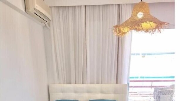 Un lit avec une tête de lit blanche, deux oreillers et une couvre-lit de couleur turquoise.