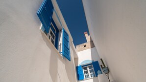 A narrow street with white buildings and blue shutters. - Holiday Home 'Naxos Family House In Vivlos' with Sea View, Wi-Fi and Air Conditioning (Naxos)