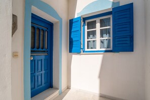 A hallway with a blue door and window, white walls, and a tiled floor. - Holiday Home 'Naxos Family House In Vivlos' with Sea View, Wi-Fi and Air Conditioning (Naxos)