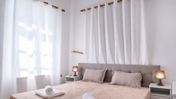 A neatly made bed with pillows, a bedside lamp, and a towel on the nightstand. - Holiday Home 'Naxos Family House In Vivlos' with Sea View, Wi-Fi and Air Conditioning (Naxos)