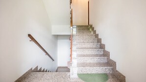 Una escalera con barandilla, peldaños alfombrados y una lámpara en la parte superior.
