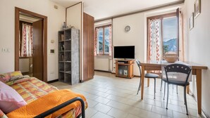 Un dormitorio con una cama, un escritorio con una silla, un televisor y una estantería.