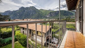 Un balcon avec vue sur les montagnes, une voiture garée et un bâtiment avec un toit en tuiles.