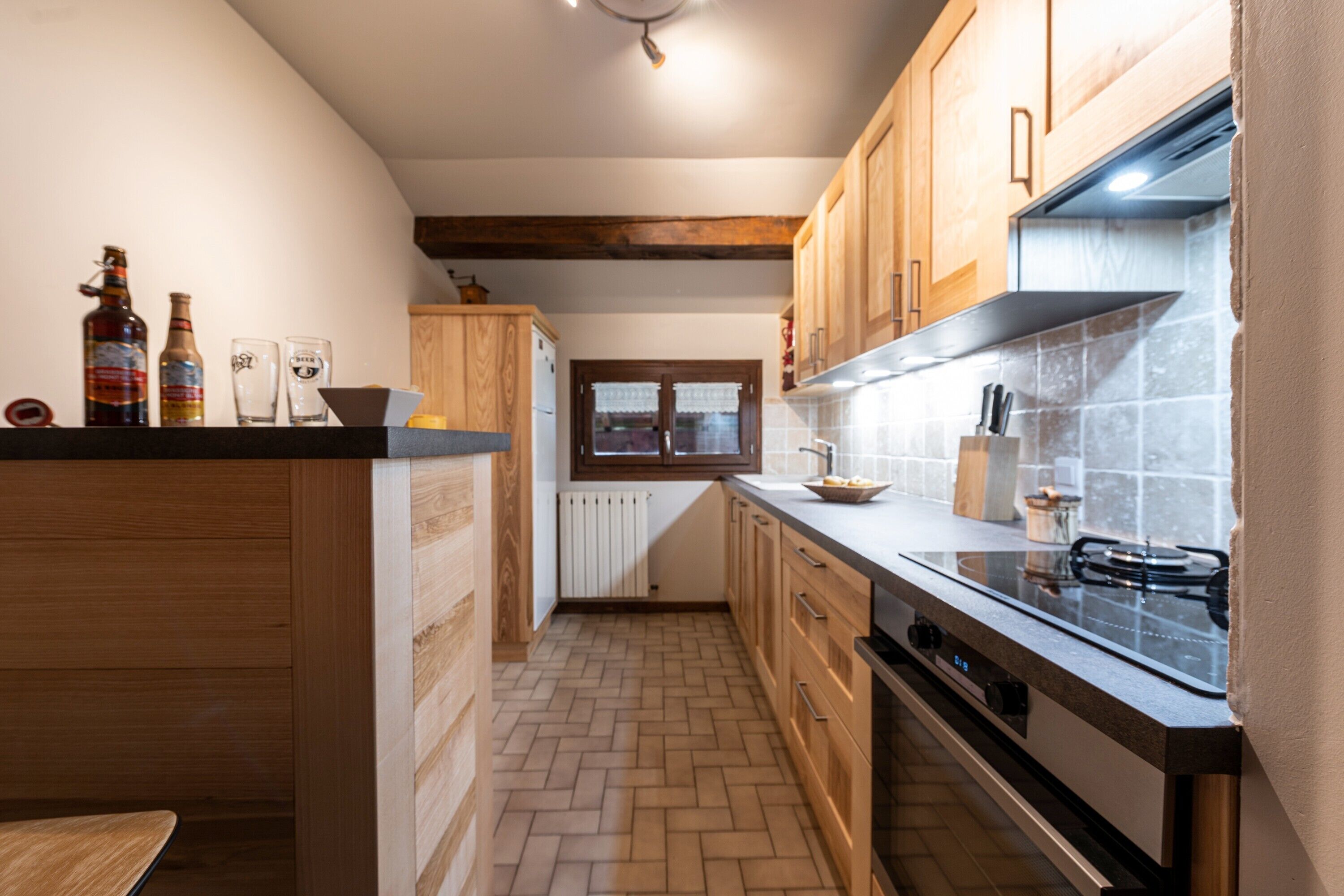 Een keuken met houten kastjes, een gasfornuis en een raam.