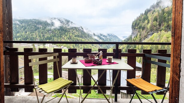 A balcony with a table set for two, overlooking a mountainous landscape. - Apartment 'Chalet Le Grand Nant' with Balcony and Wi-Fi (La Giettaz)