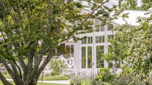 A modern building with large windows and a well-maintained garden with various plants and a tree. - Isca House, Exeter, NSW, Isca House, Exeter (Exeter)