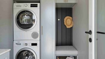 A laundry room with stacked washing machines, a hat on the wall, and a checkered floor.