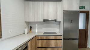 Una cocina moderna con armarios blancos, un refrigerador de acero inoxidable y un horno empotrado.