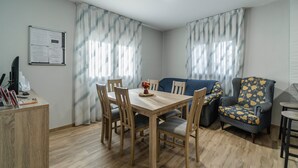 Un comedor con mesa de madera, sillas, un sofá y un sillón estampado.