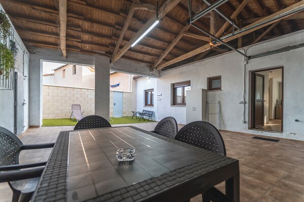 An indoor patio area with a long table, chairs, and a ceiling with exposed beams.
