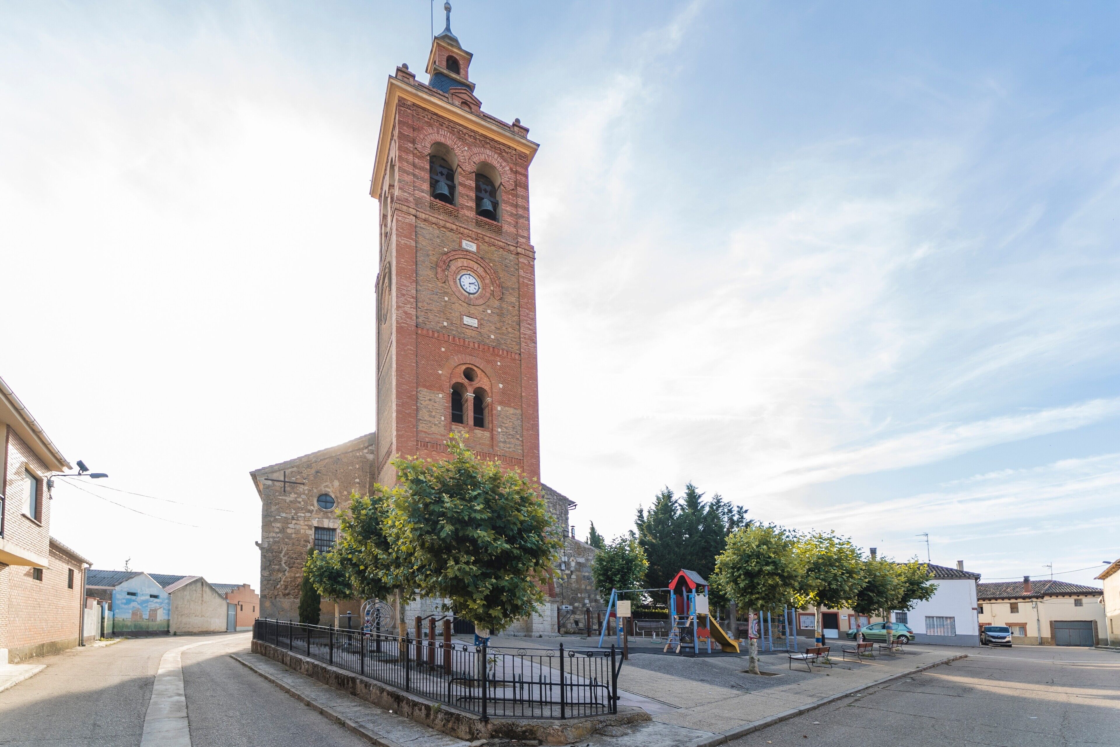 Una torre histórica con un reloj, rodeada de un parque infantil y edificios residenciales.