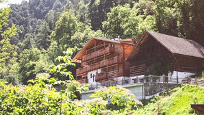 A wooden chalet with a balcony, set against a forested hillside. - Apartment 'Die Jocherin' with Mountain View, Private Terrace and Shared Garden (San Pancrazio)