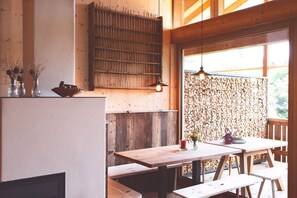 Un intérieur en bois avec une cheminée, des bancs en bois et une table éclairée par une bougie.