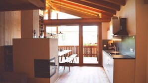 A kitchen with wooden flooring, a dining area with a table and chairs, and a view through a glass door to an outdoor area. - Apartment 'Die Jocherin' with Mountain View, Private Terrace and Shared Garden (San Pancrazio)