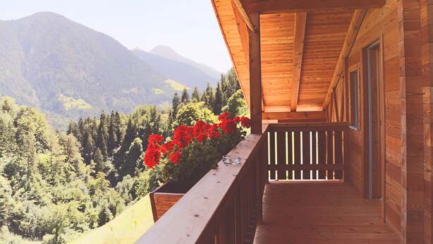 A wooden cabin with a balcony overlooking a forested mountain landscape. - Apartment 'Die Jocherin' with Mountain View, Private Terrace and Shared Garden (San Pancrazio)