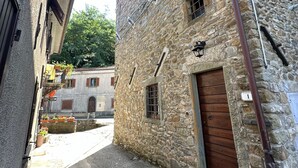 Une ruelle pavée étroite, bordée d’un bâtiment doté d’une porte en bois et d’une petite fenêtre.